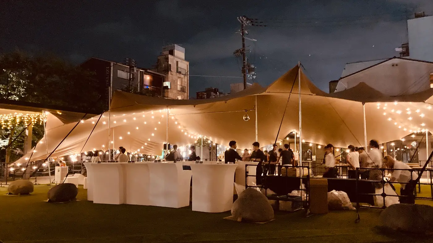 夜、照明で光るストレッチテントとパーティーのゲスト